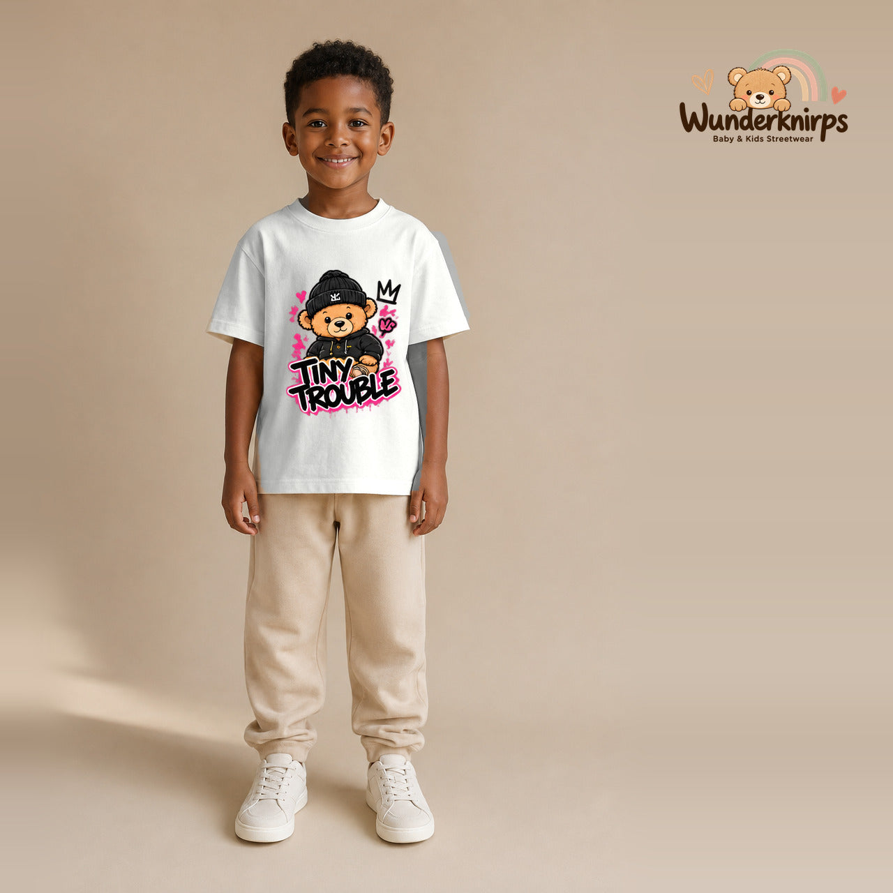 T-Shirt für Jungen in Weiß mit Motiv „Tiny Trouble“, getragen von einem Kind – Wunderknirps.
