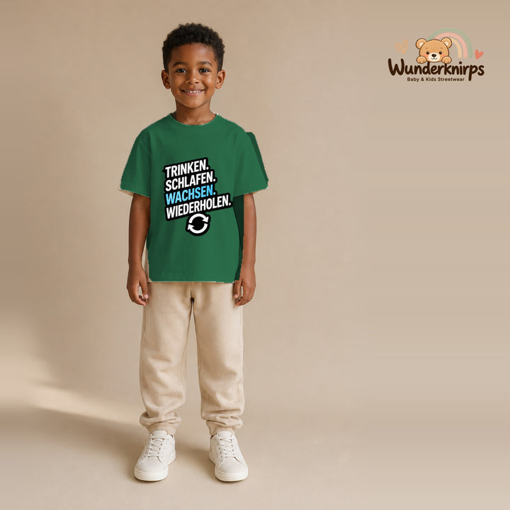 T-Shirt für Jungen in Grün mit Motiv „Trinken Schlafen Wachsen“, getragen von einem Kind – Wunderknirps.