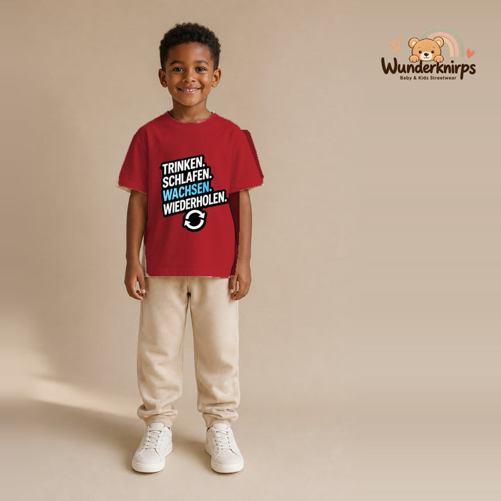 T-Shirt für Jungen in Rot mit Motiv „Trinken Schlafen Wachsen“, getragen von einem Kind – Wunderknirps.