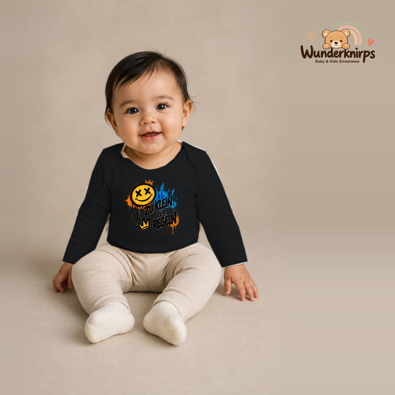 Babybody für Mädchen in Schwarz mit Motiv „Zu klein für Regeln“, getragen von einem Kind – Wunderknirps.