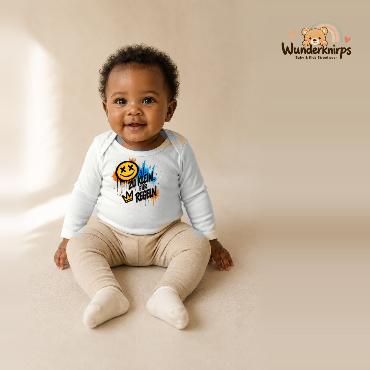 Babybody für Mädchen in Weiß mit Motiv „Zu klein für Regeln“, getragen von einem Kind – Wunderknirps.